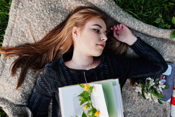 Young brunette girl lying on plaid with book. - Φωτογραφία, εικόνα