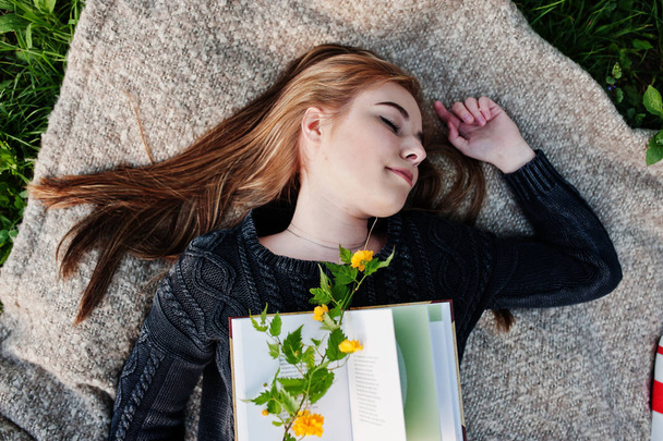 Young brunette girl lying on plaid with book. - Foto, afbeelding