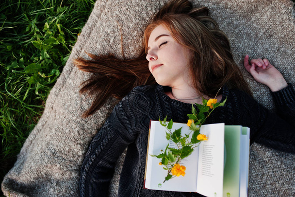 Young brunette girl lying on plaid with book. - Фото, зображення
