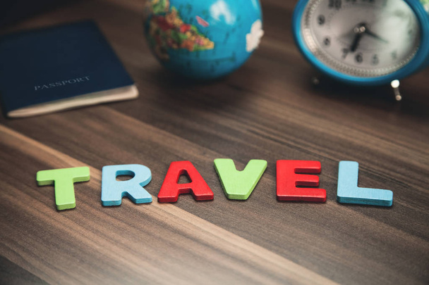 Kleurrijke woord reiswekker met paspoort en globe op de houten achtergrond. - Foto, afbeelding