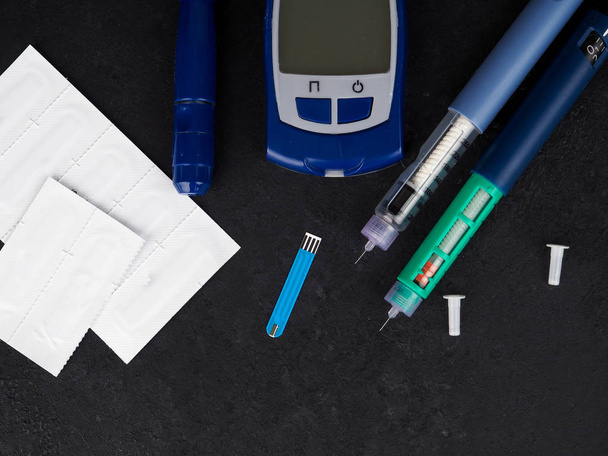 orvoslás, cukorbetegség, reklám- és egészségügyi koncepció - zár-megjelöl-ból glükométer vércukor teszt csík, az inzulin injekció fecskendők és tabletták a táblázat. - Fotó, kép