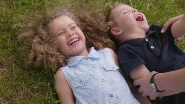 Crianças felizes estão deitadas na grama e rindo em câmera lenta
 - Filmagem, Vídeo