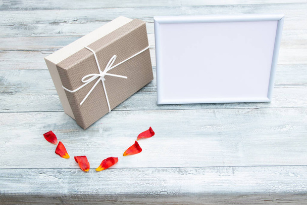 Gift box and white frame with place for your text on rustic bright wooden table. Card concept.   - Φωτογραφία, εικόνα