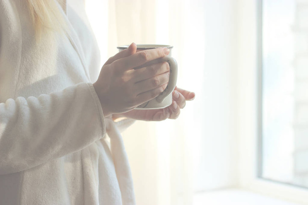 a cup of tea or coffee in female hands on the window background. Morning, pajamas, minimalism. insta - Фото, зображення