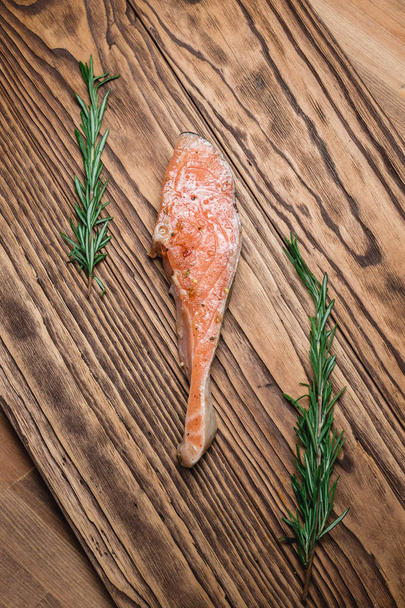 Filé de salmão cru com alecrim, pimenta e sal em tábua de corte de madeira. de perto
 - Foto, Imagem