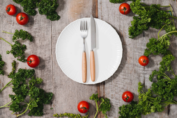 新鮮な季節の有機野菜、光の素朴な背景にナイフとフォーク プレート トップ ビュー - 写真・画像