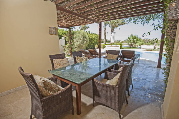Ylellinen huvila näyttää kotiin trooppinen kesäloma keinona uima-allas ja ulkona ruokapöytä alue
 - Valokuva, kuva