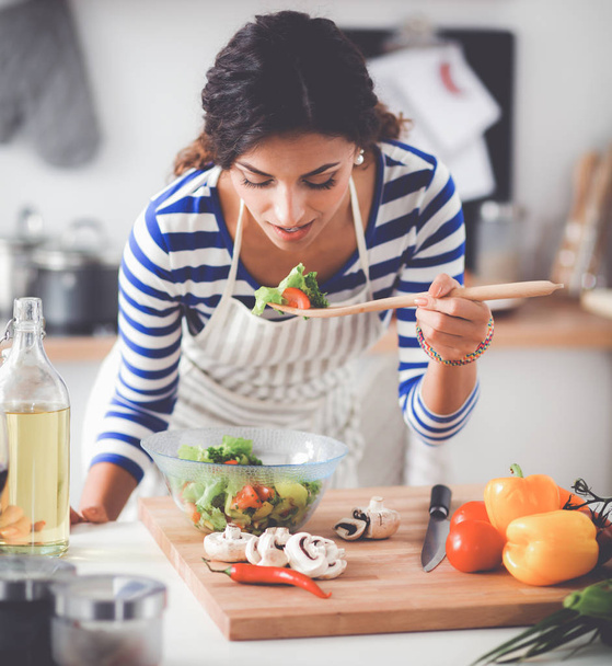 Young woman eating fresh salad in modern kitchen - Photo, image