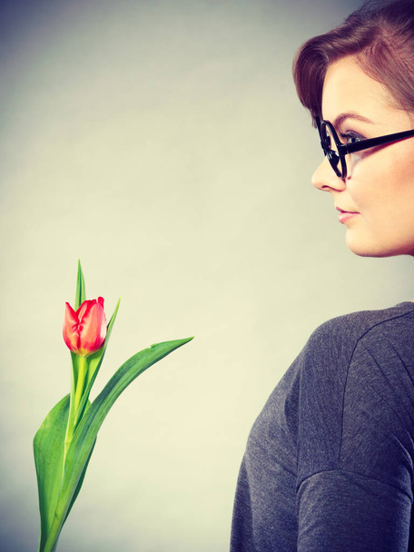 Люди і квіти. Дівчинка обожнює природу, тримаючи весняну квітку червоного зеленого тюльпана. Жінка, що обожнює природне середовище
. - Фото, зображення