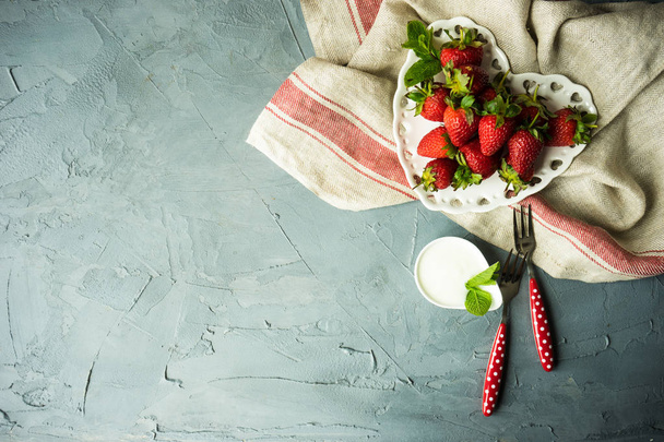 Heart shaped bowl with fresh organic strawberry, mint herb amd cream as a healthy food concept - 写真・画像