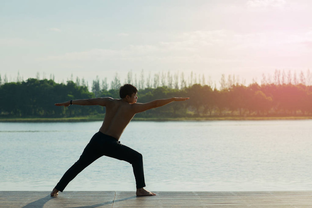 Young man is practicing yoga at river.man yoga - relax in nature - Valokuva, kuva