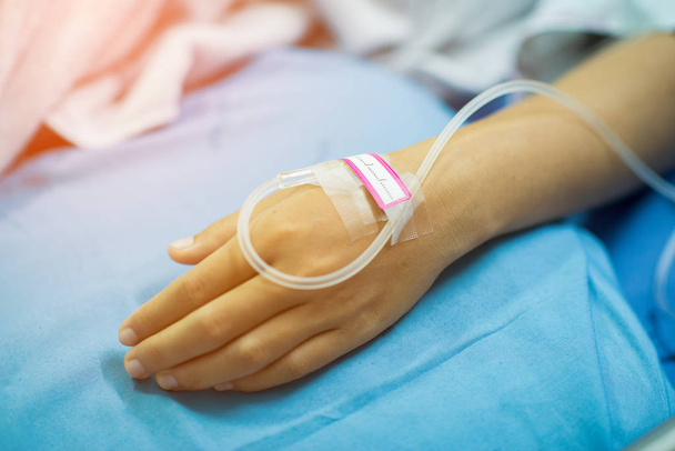 bliska roztworu soli fizjologicznej na rękę azjatyckich kobiet pacjenta leżącego na szpitalnym łóżku - Zdjęcie, obraz