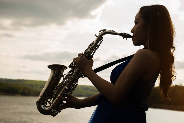 Kobieta gra saksofon saksofon na zachód, koncepcja życia muzyka. - Zdjęcie, obraz