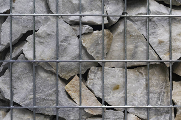 Kivinen tausta. Puukotettu harmaita kiviä takana metalli ristikko
 - Valokuva, kuva