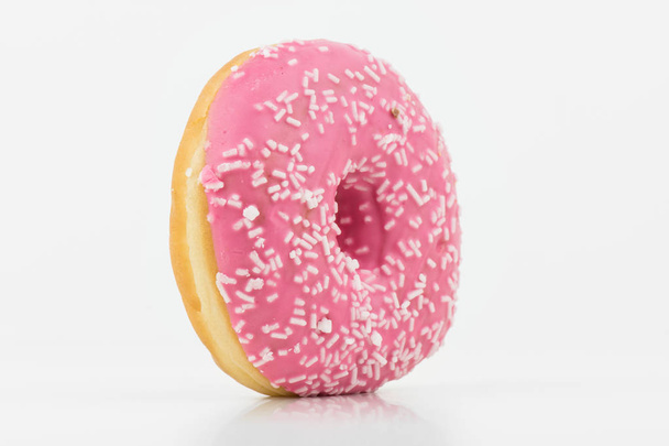 Nahaufnahme von köstlichen rosafarbenen Donut auf weißem Hintergrund mit weißer Schokolade darauf. isoliert auf weiß - Foto, Bild