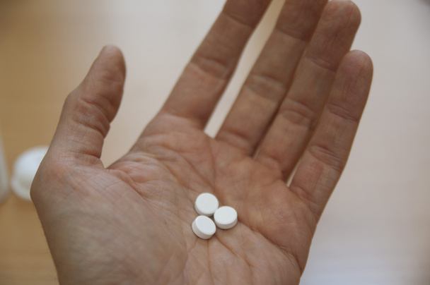 Close up view of Arnica pills in hand - Photo, Image