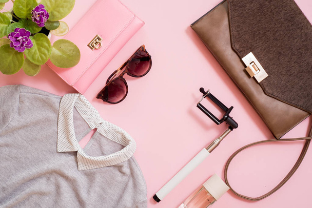 set clothes, a purse and a bag, a comb and sunglasses, a self-stick and eau de toilette. Flowers are next to a pink background. Fashion trends of summer for the women - Zdjęcie, obraz