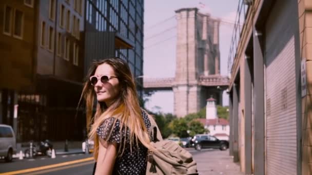 Camera follows happy Caucasian girl in fashionable sunglasses with hair blowing in the wind in New York City slow motion - Video