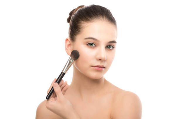 Young brunette woman with clean face. Girl perfect skin applying cosmetic brush. Isolated on a white. - Foto, afbeelding