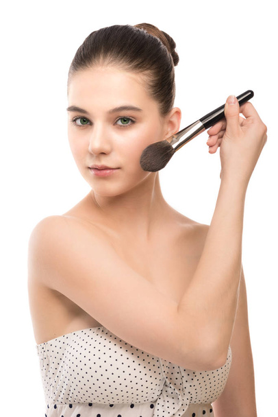Young brunette woman with clean face. Girl perfect skin applying cosmetic brush. Isolated on a white. - Photo, Image
