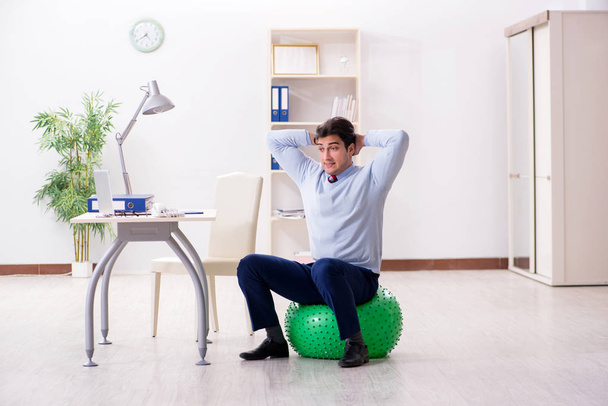 Employee exercising with swiss ball during lunch break - Photo, Image