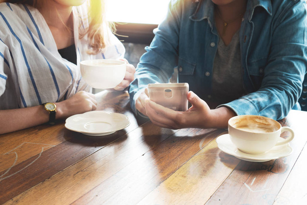 Mitarbeiterinnen Junge Frauen aus der Wirtschaft arbeiten im Café mit dem Smartphone. Meeting und Brainstorming Teamwork-Konzept. neues Start-up Online Marketing Projekt. Vintage-Film-Effekt - Foto, Bild