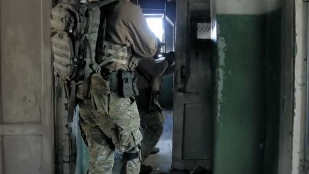 Soldaten in camouflage met bestrijding wapens sluipen langs de gangen van het oude gebouw, het militaire concept - Video