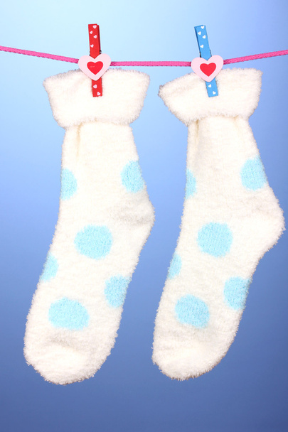 Pair of socks with polka dots hanging to dry over blue background - Фото, зображення