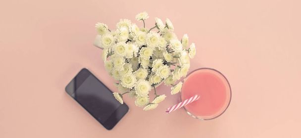 Banner μπουκέτο λουλουδιών χρυσάνθεμο σε ένα φλιτζάνι τσάι ποτήρι κοκτέιλ τηλέφωνο. Φεστιβάλ ροζ φόντο κάτοψη επίπεδης lay - Φωτογραφία, εικόνα