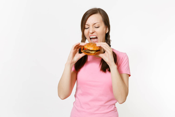 Mooie jongedame met open mond houden in handen hamburger, proberen te eten geïsoleerd op witte achtergrond. Goede voeding of Amerikaanse klassieke fastfood. Kopieer de advertentie ruimte. Gebied van de reclame - Foto, afbeelding