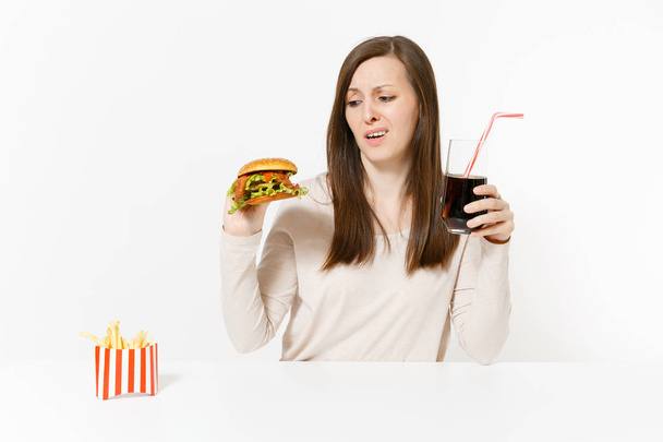 Masada oturan hamburger, patates kızartması, cam şişede cola ile memnun kadın beyaz arka plan üzerinde izole. Doğru beslenme veya Amerikan Klasik fast food. Alan kopya alanı ile reklam - Fotoğraf, Görsel