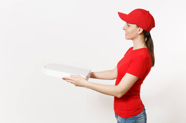 Delivery woman in red uniform isolated on white background. Pretty female in cap, t-shirt, jeans working as courier or dealer holding italian pizza in cardboard flatbox. Copy space for advertisement - Fotó, kép