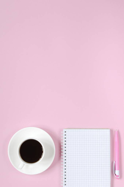 Open notebook with pink pen and coffee cup on pink background. Copy space background, top view flat lay overhead - Zdjęcie, obraz