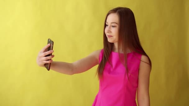 Young beautiful lady standing isolated over yellow background while make selfie by phone. - Filmmaterial, Video