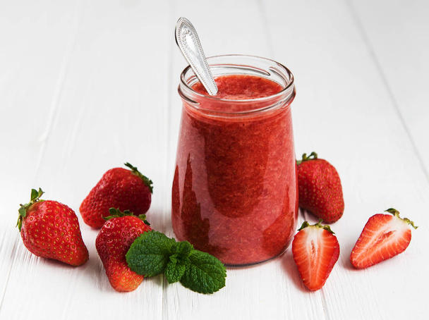 Jar with strawberry smoothie on a white wooden table - Фото, зображення