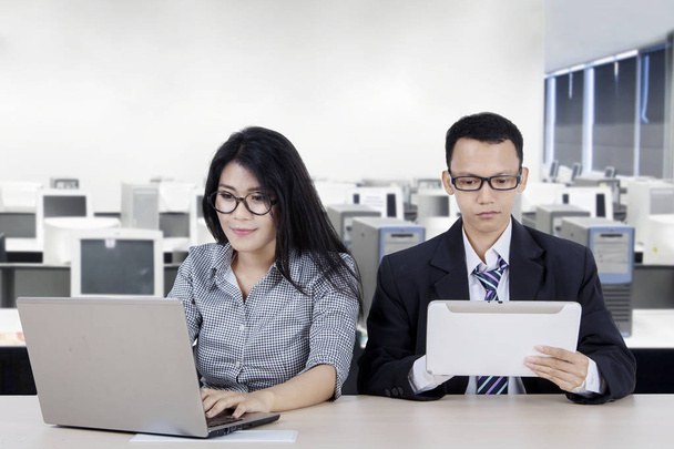 Portrait of young business couple using digital device while working in the office - 写真・画像