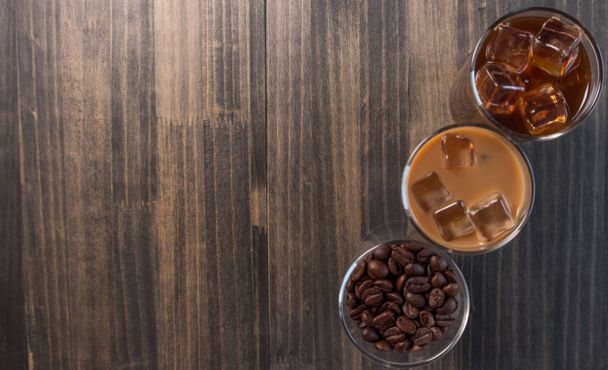 Μαύρο παγωμένο καφέ, κρύο latte και φασόλια πέρα από το ξύλινο υπόβαθρο - Φωτογραφία, εικόνα