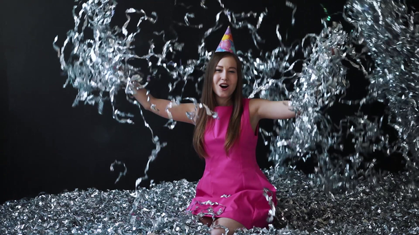 Jovem feliz em vestido rosa celebra Ano Novo ou aniversário em fundo preto com confete
 - Filmagem, Vídeo