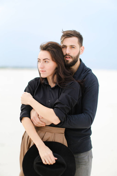 Portrait of american man hugging woman in monophonic winter background. Concept of seasonal romantic photo session and feelings. - Foto, Imagem