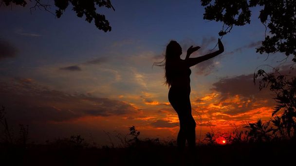 Silhouette féminine méditant le soir et faisant du yoga au coucher du soleil
. - Photo, image