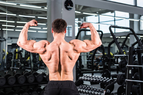 Bodybuilder man met perfecte biceps, triceps en borst in de sportschool - Foto, afbeelding
