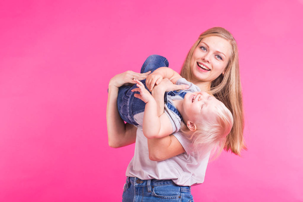 Забавная семейка на розовом фоне. Мать и ее дочь девочка. Мама и ребенок веселятся
. - Фото, изображение