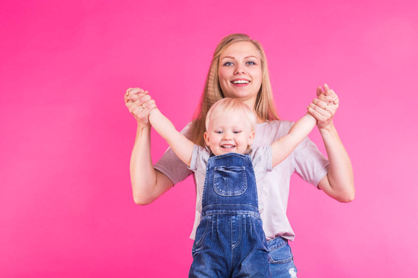 happy little girl and her mother having fun over pink background - Foto, Imagen