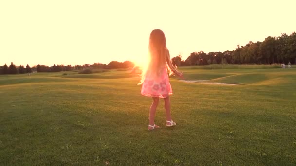 Cute schoolchild spinning on green meadow. - Footage, Video