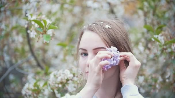 Portrait of young woman in garden - girl sticks a sprig of lilac in her hair - Footage, Video