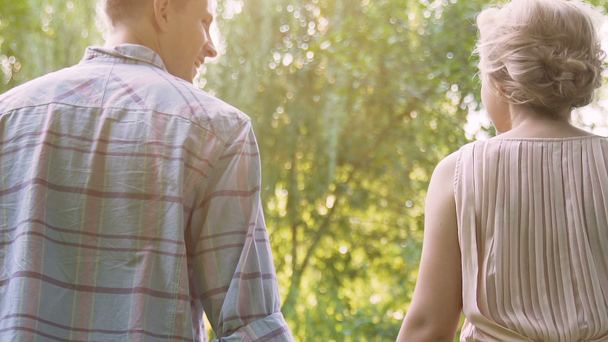 Smiling couple walking in summer forest holding picnic basket back view, date - Footage, Video