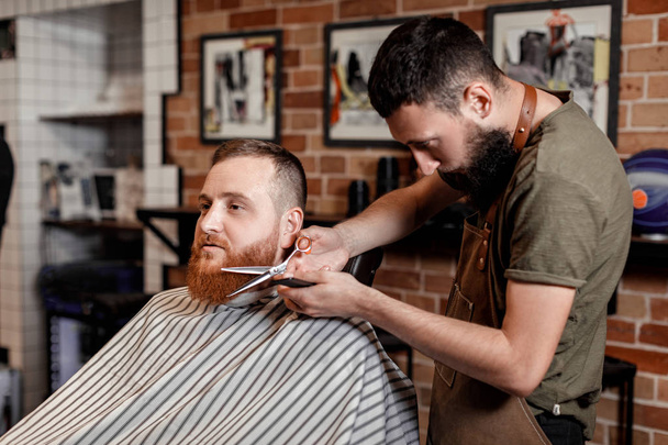Barber and bearded man in barber shop - Фото, изображение