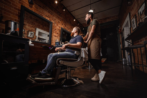 Barber and bearded man in barber shop - Foto, afbeelding