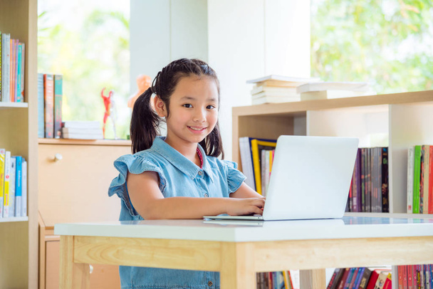 Giovane ragazza asiatica utilizzando computer portatile in biblioteca
 - Foto, immagini