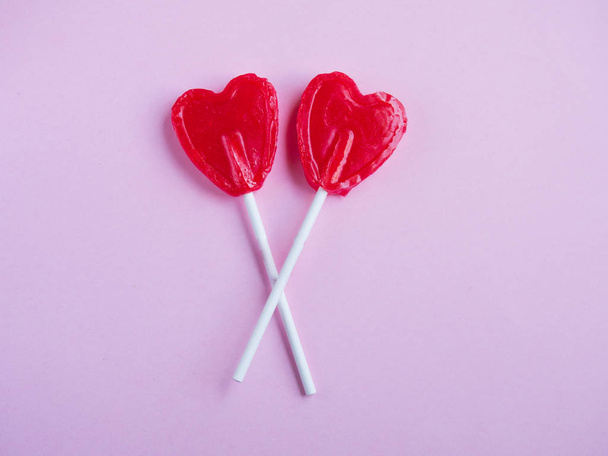 Два красных сердечка леденец на розовом фоне
 - Фото, изображение